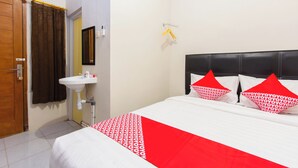 Una habitación de hotel con cama, mesita de noche, espejo, lavabo y puerta.