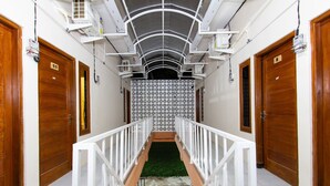 A corridor with wooden doors, a white railing, and a patterned wall. - Oyo 1718 Homestay Wak Gobenk (Depok)