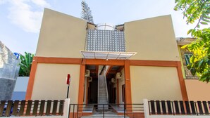 A building with a central staircase, a patterned wall, and a gated entrance. - Oyo 1718 Homestay Wak Gobenk (Depok)