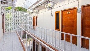A corridor with a white railing, wooden doors, and air conditioning units. - Oyo 1718 Homestay Wak Gobenk (Depok)