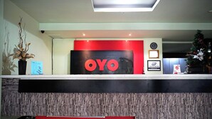 A reception desk with a 'OYO' sign, a potted plant, and a framed certificate on the wall. - OYO 2015 Bandara Hotel Balikpapan (Balikpapan)