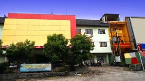 A hotel with a large signboard, multiple floors, and a parking area with motorcycles. - OYO 2015 Bandara Hotel Balikpapan (Balikpapan)