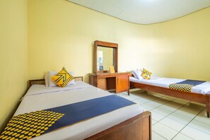 A room with two beds, a wooden desk, and a mirror. - Oyo 1970 Hotel Priangan (Tasikmalaya)