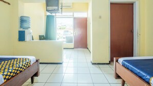 Quarto de hotel com duas camas, televisão, dispensador de água e vista para o exterior.