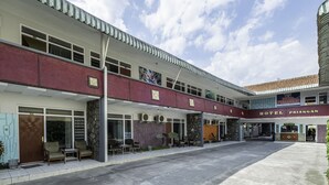 Un hôtel à deux étages, doté d’une réception et d’un espace extérieur aménagé pour s’asseoir.