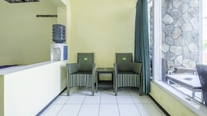 Un petit balcon fermé, équipé de deux fauteuils en osier et d’une petite table, ainsi que d’un distributeur d’eau et d’un mur en pierre.