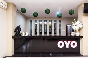 Un mostrador de recepción con superficie negra, espejos verticales y el logotipo 'OYO'.