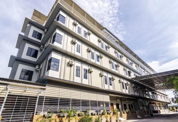 A multi-story hotel with balconies, air conditioning units, and a covered entrance.