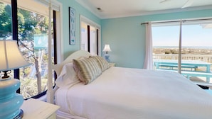 Ein Schlafzimmer mit einem großen Bett, einem Deckenventilator und Blick auf den Strand.
