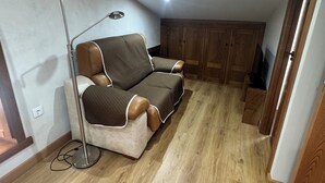 Un acogedor espacio tipo loft con sofá, una lámpara de pie y piso de madera.