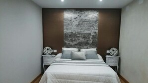 Un dormitorio moderno con una cama grande, dos mesitas de noche y un mural decorativo en la pared.