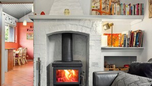 A cozy living room with a fireplace, a bookshelf, and a leather sofa. - CROFT COTTAGE near Hepburn Mineral Springs Reserve (Hepburn Springs)