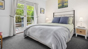 A bedroom with a bed, two bedside tables, a window with curtains, and a painting on the wall. - CROFT COTTAGE near Hepburn Mineral Springs Reserve (Hepburn Springs)