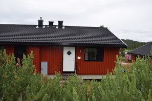 A red building with a white door, a chimney, and a small window.