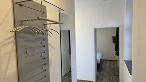 A hallway with a modern shower area, a glass shower enclosure, and a mirror reflecting the room.