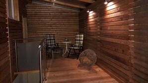 A cozy cabin interior with wooden walls, a small dining area with two chairs and a table, and a decorative ball on the floor.