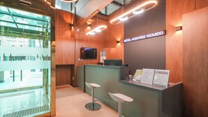 A reception desk with a sign reading 'HOTEL AVENUE YEUYIDO,' a television mounted on the wall, and two stools in front of the desk. - Hotel Aventree Yeouido (Seoul)