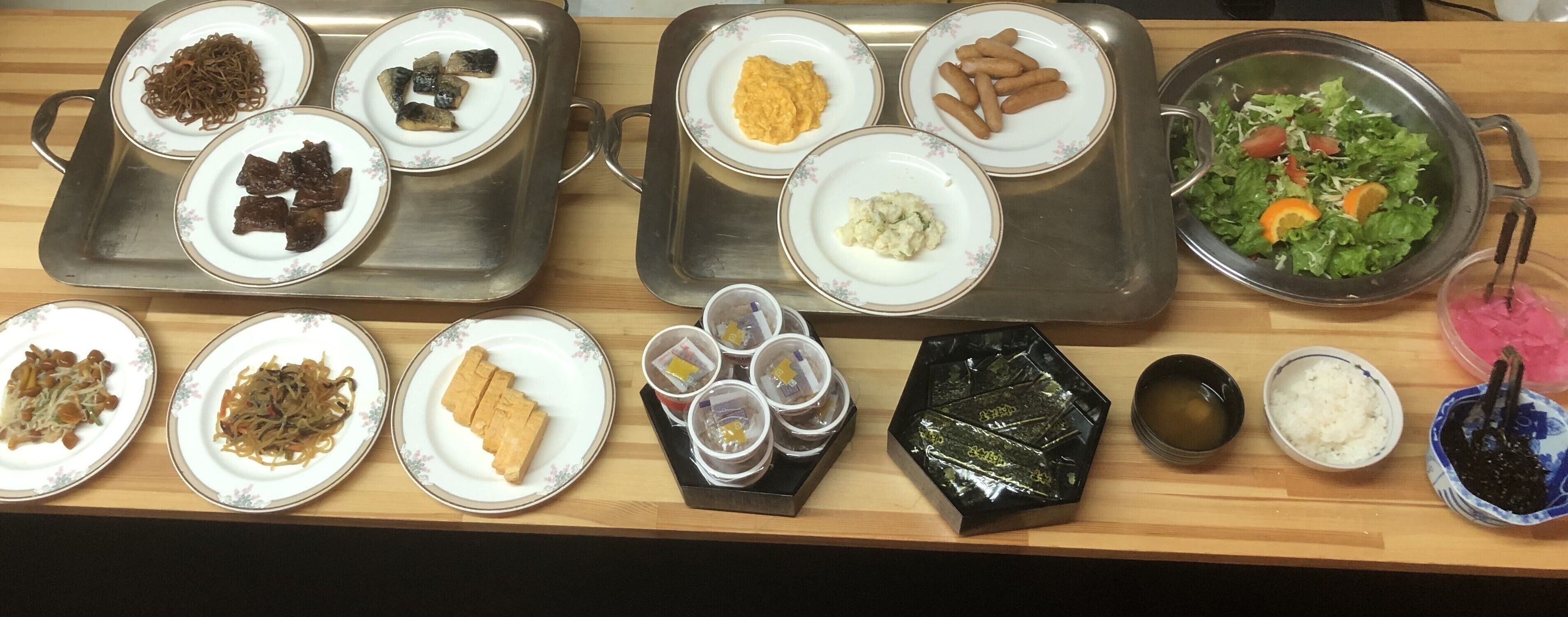 Diversos pratos em uma bandeja, incluindo macarrão, carne e legumes.