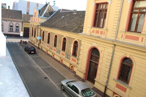 A street view with a yellow building featuring arched windows and a red door. - Nikolajevska (Novi Sad)