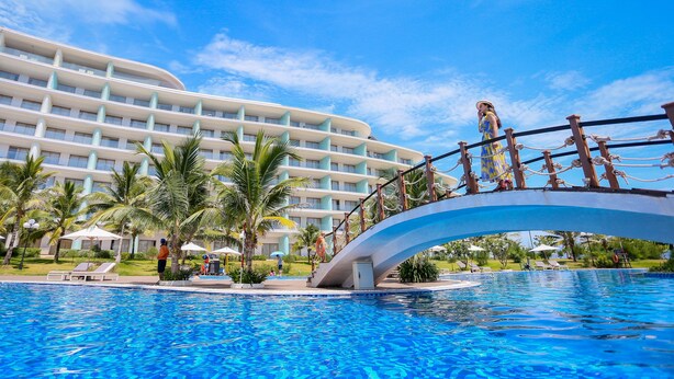 Ein Hotel mit Pool, Palmen und einer Brücke.