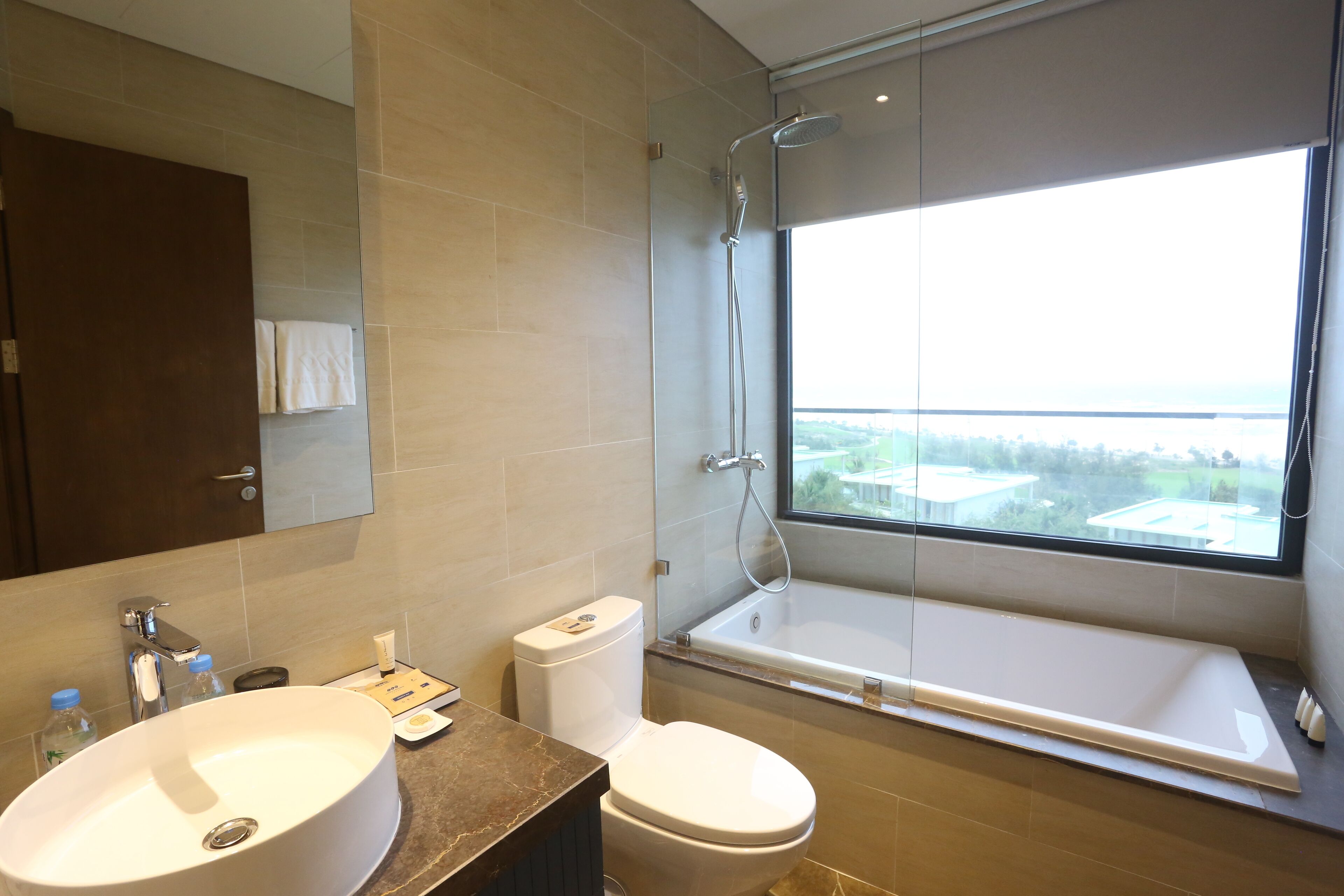 A modern bathroom with a large window, a bathtub, and a sink.