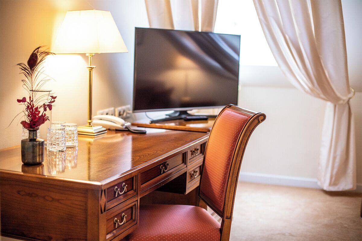 Ein Holztisch mit einem Laptop, einer Lampe und einer Blumenvase.