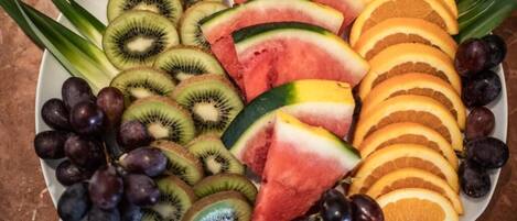 A plate of sliced fruits including kiwi, watermelon, grapes, and orange slices.