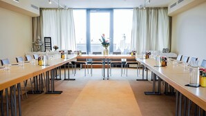 A conference room with a long table, chairs, and a view through large windows. - Altstadthotel Weinhaus Messerschmitt (Bamberg)