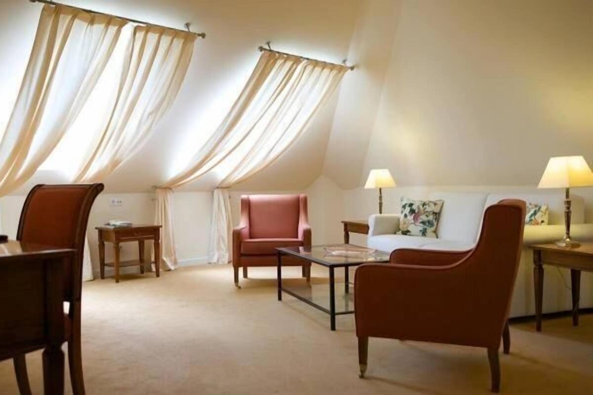 Ein gemütliches Wohnzimmer mit einer Couch, zwei Sesseln, einem Couchtisch und einer Lampe.