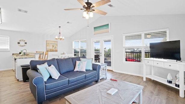 A spacious living room with a sofa, coffee table, TV, ceiling fan, and a view of the outdoors. - Beach house with ground floor mother in law suite! (Port St Joe)