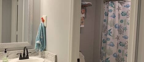 A bathroom with a white sink, a mirror, and a shower curtain with a marine life pattern.