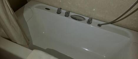 A bathtub with a shower curtain, a towel, and a grab bar on the wall.