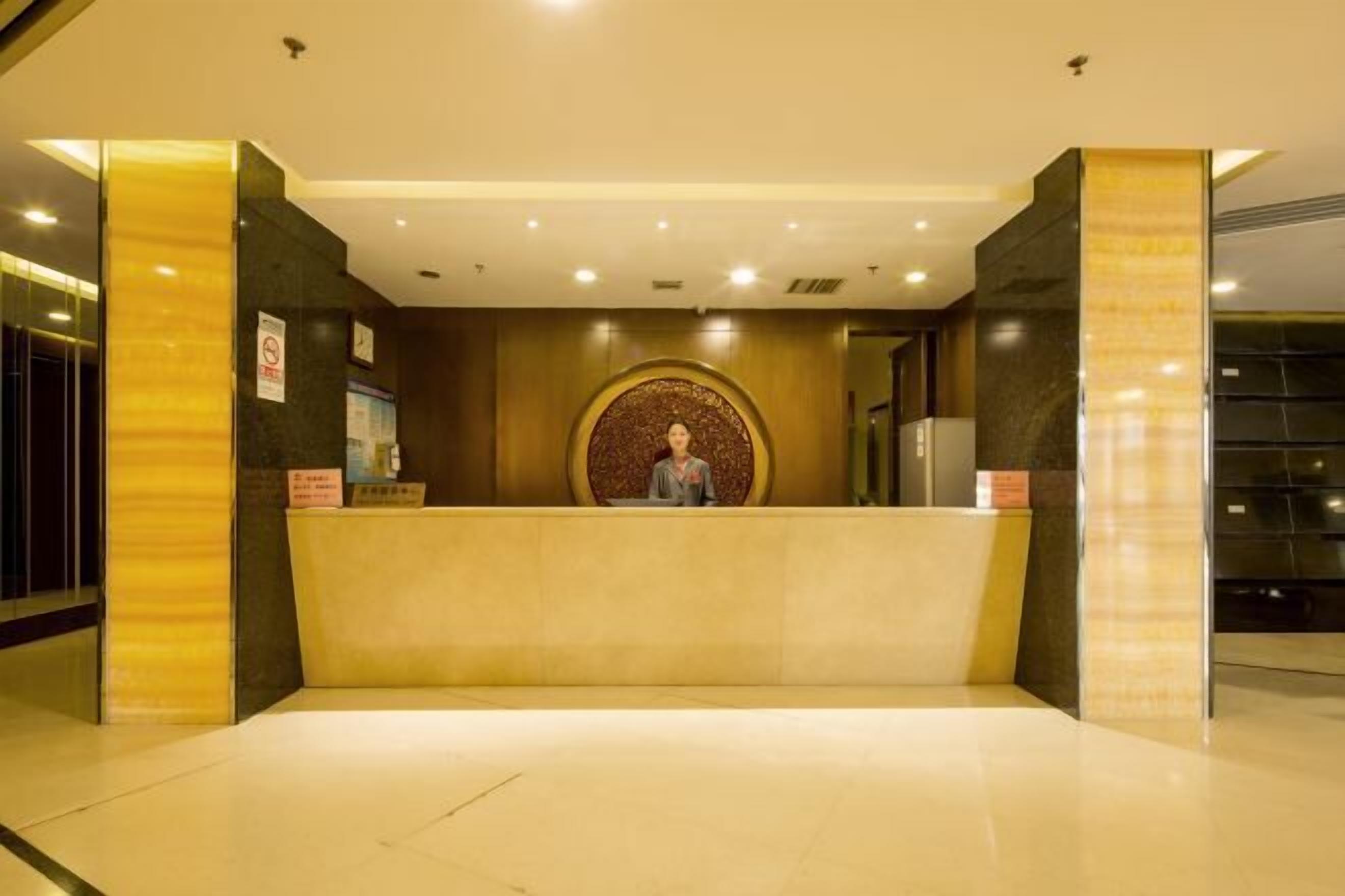 A hotel reception area with a marble counter, a clock, and a sign indicating a no-smoking policy.