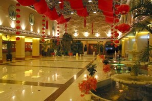 A spacious lobby with a fountain, red lanterns, and a large mirror. - Dong Fang Hotel (Beijing)