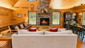Ein gemütliches Blockhaus-Interieur mit Kamin, Holzwänden, einer Couch und einem Essbereich.
