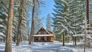 Eine Holzhütte, umgeben von schneebedeckten Bäumen.