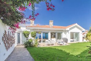 Ein modernes Haus mit Terrasse, Essbereich und Meerblick.