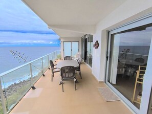 Ein Balkon mit Tisch und Stühlen mit Blick auf die Küste.