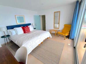 Ein Hotelzimmer mit Bett, Stuhl, kleinem Tisch, Spiegel und Blick nach außen.