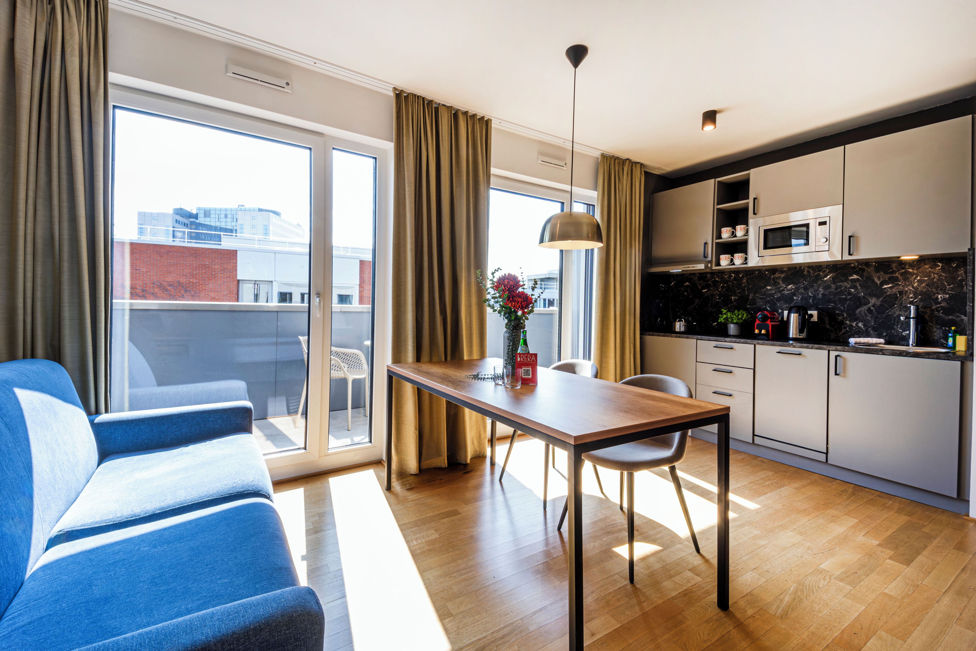 A modern kitchen with a microwave, cabinets, and a dining area with a table and chairs.