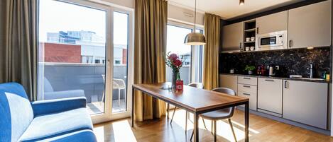 A modern kitchen with a microwave, cabinets, and a dining area with a table and chairs.