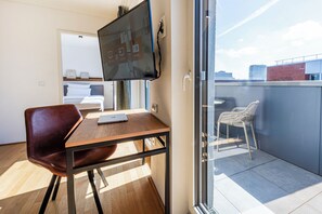 Habitació moderna amb escriptori, cadira i televisió penjada a la paret.