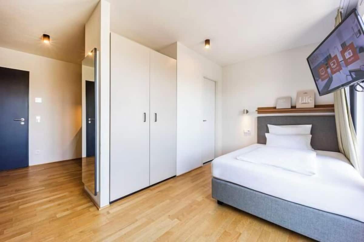 Una habitación de hotel moderna con cama, televisor y armario.