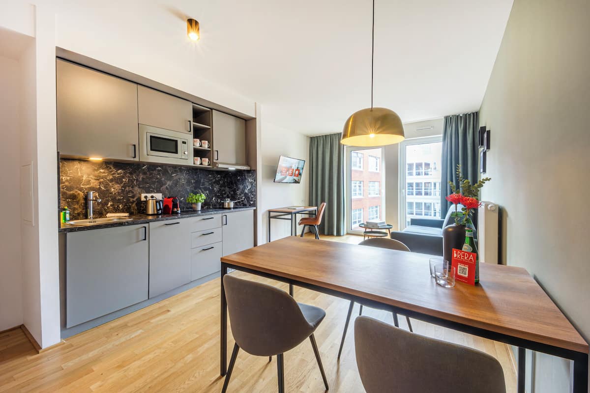 Una cocina moderna con una mesa de comedor de madera, dos sillas y una lámpara colgante.