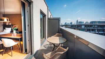 A balcony with a dining area, including a table and chairs, and a city view.