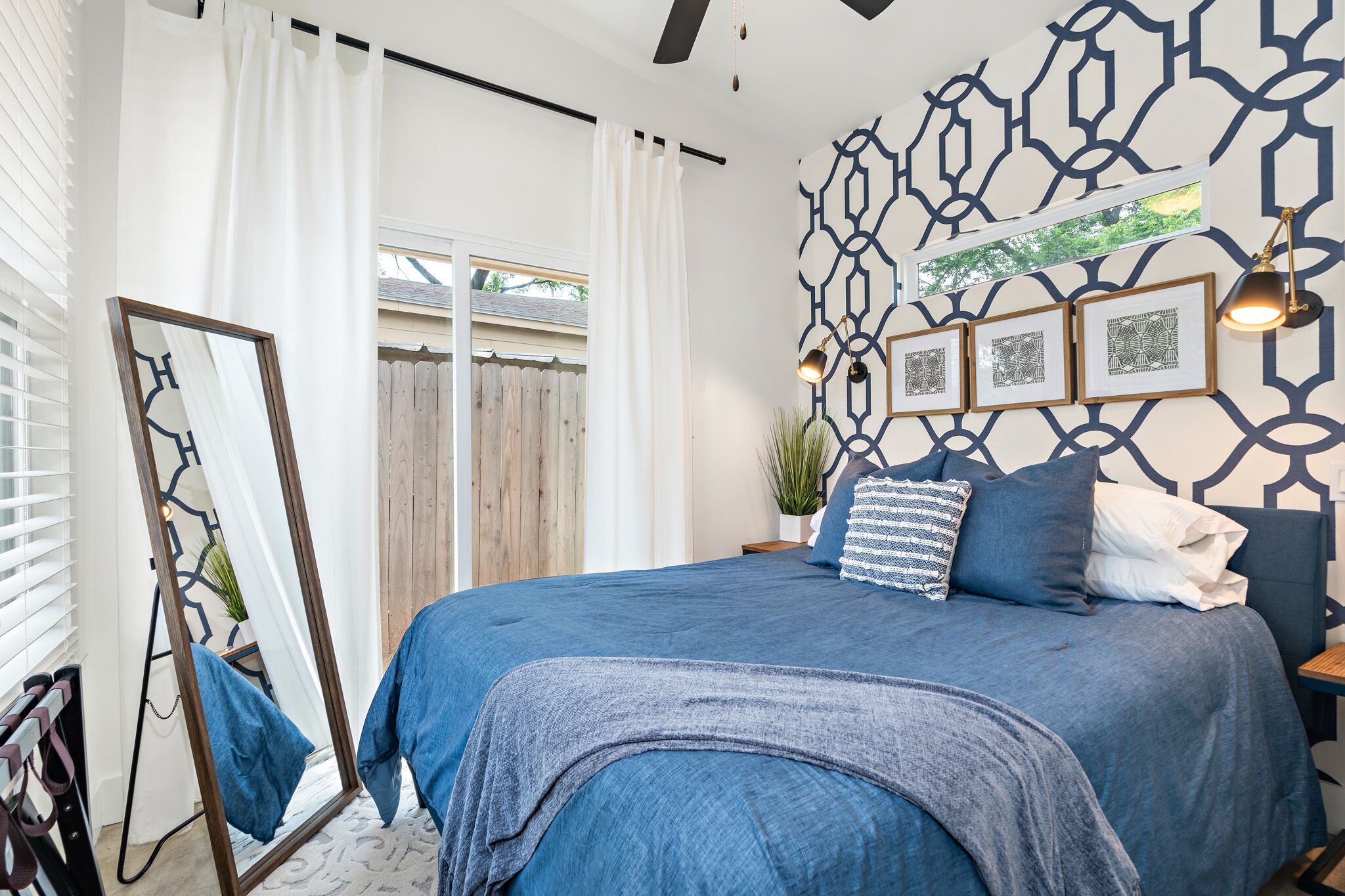 Un dormitorio con una cama grande, un espejo y un diseño geométrico en la pared.