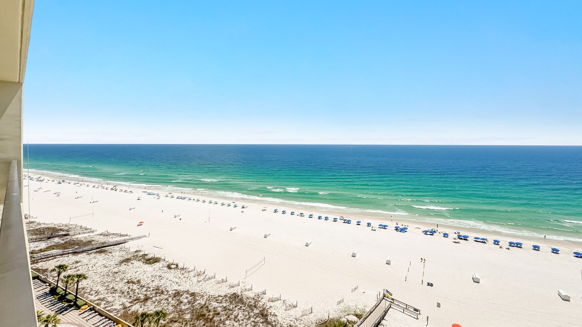 A beach view with a clear sky, sandy beach, and ocean.