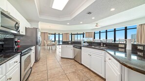 Cocina moderna con isla central, electrodomésticos integrados y ventanas amplias que ofrecen vistas.