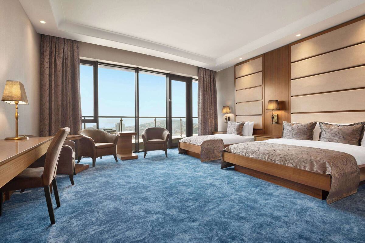 Une chambre d’hôtel avec deux lits, un bureau et une chaise.