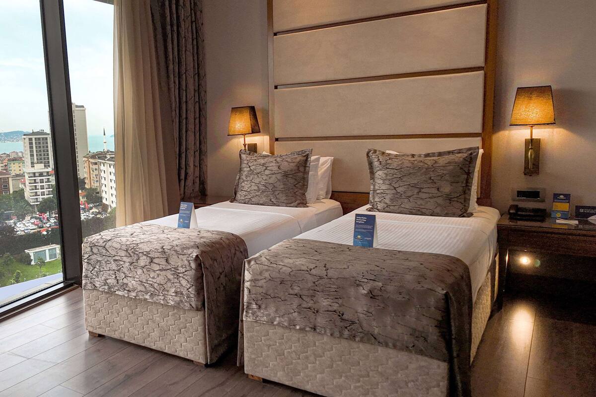 Une chambre d’hôtel avec deux lits, une grande fenêtre et une vue sur la ville.